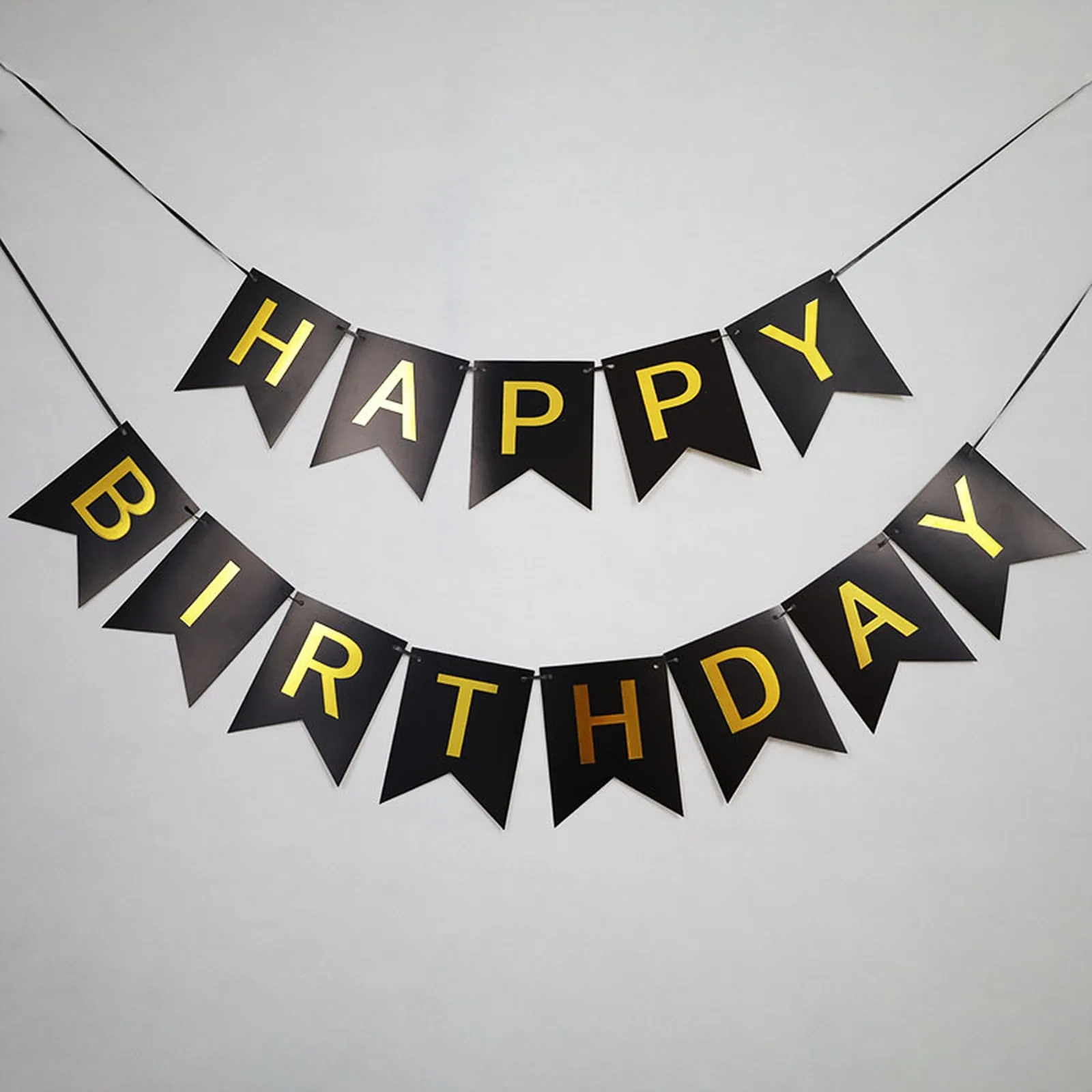 Black Happy Birthday pennant banner with gold foil letters hung in two rows