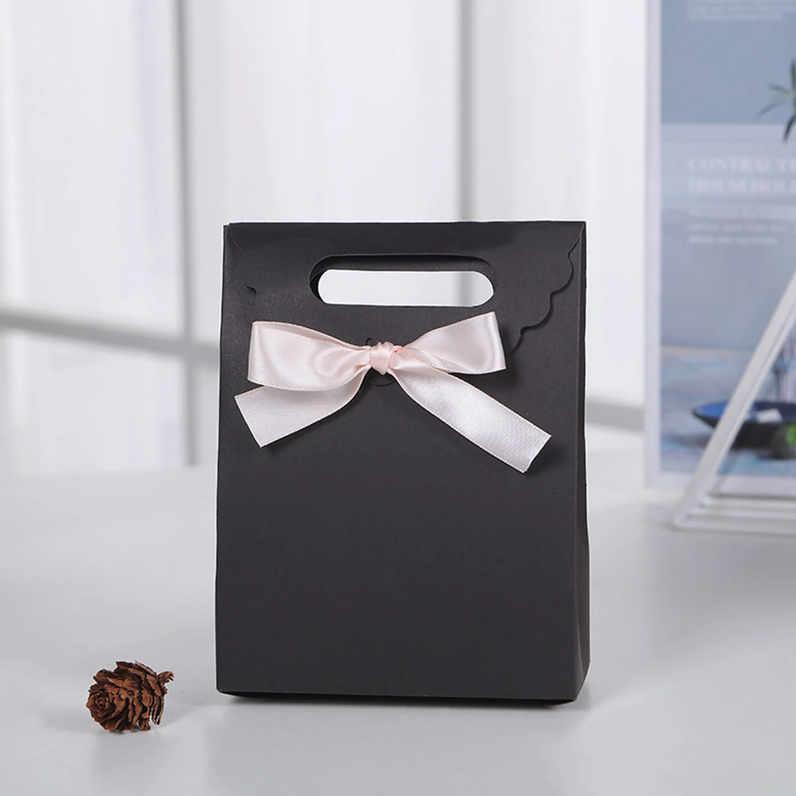 Black paper gift bag with pink satin bow and scalloped flap