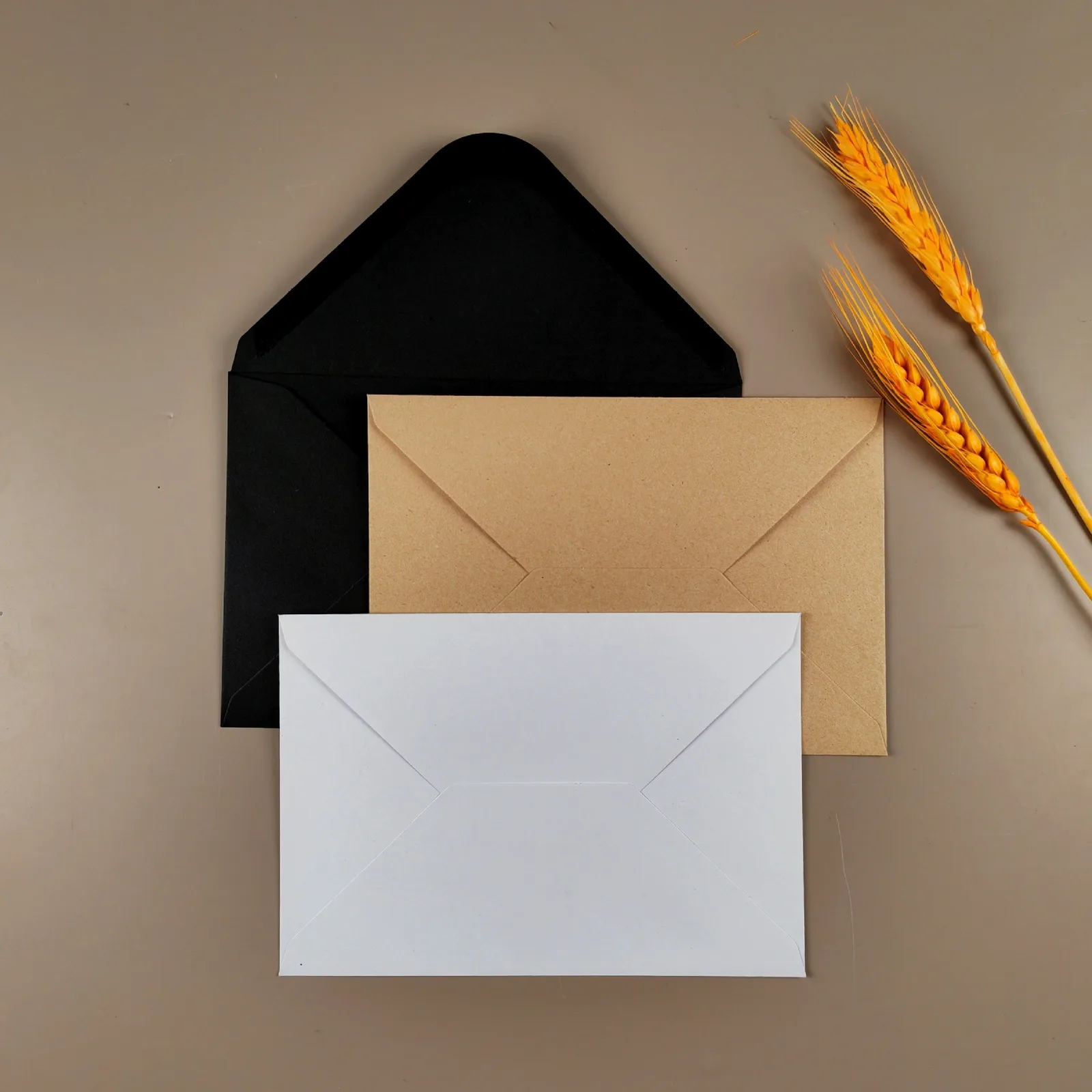 Black, kraft and white envelopes on a taupe background