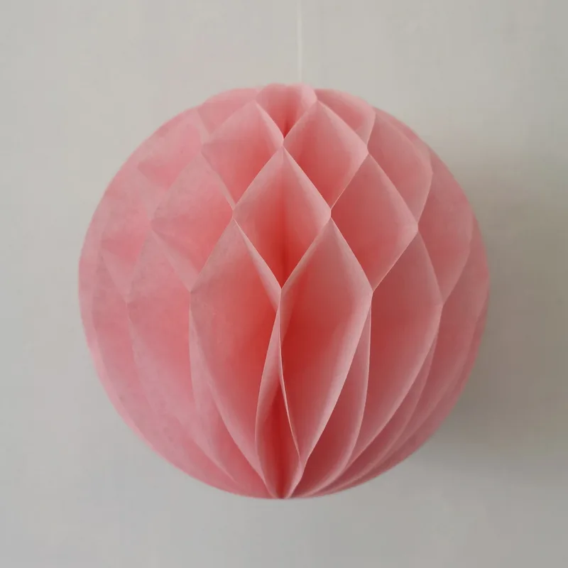 Light pink honeycomb tissue paper ball hanging on a string