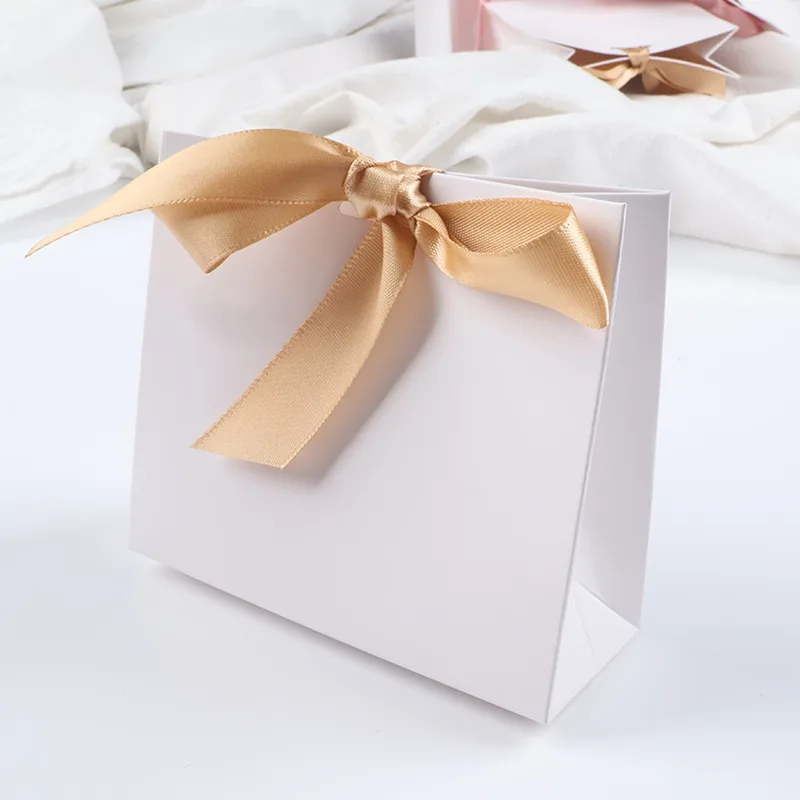 White mini gift bag tied with a gold satin bow