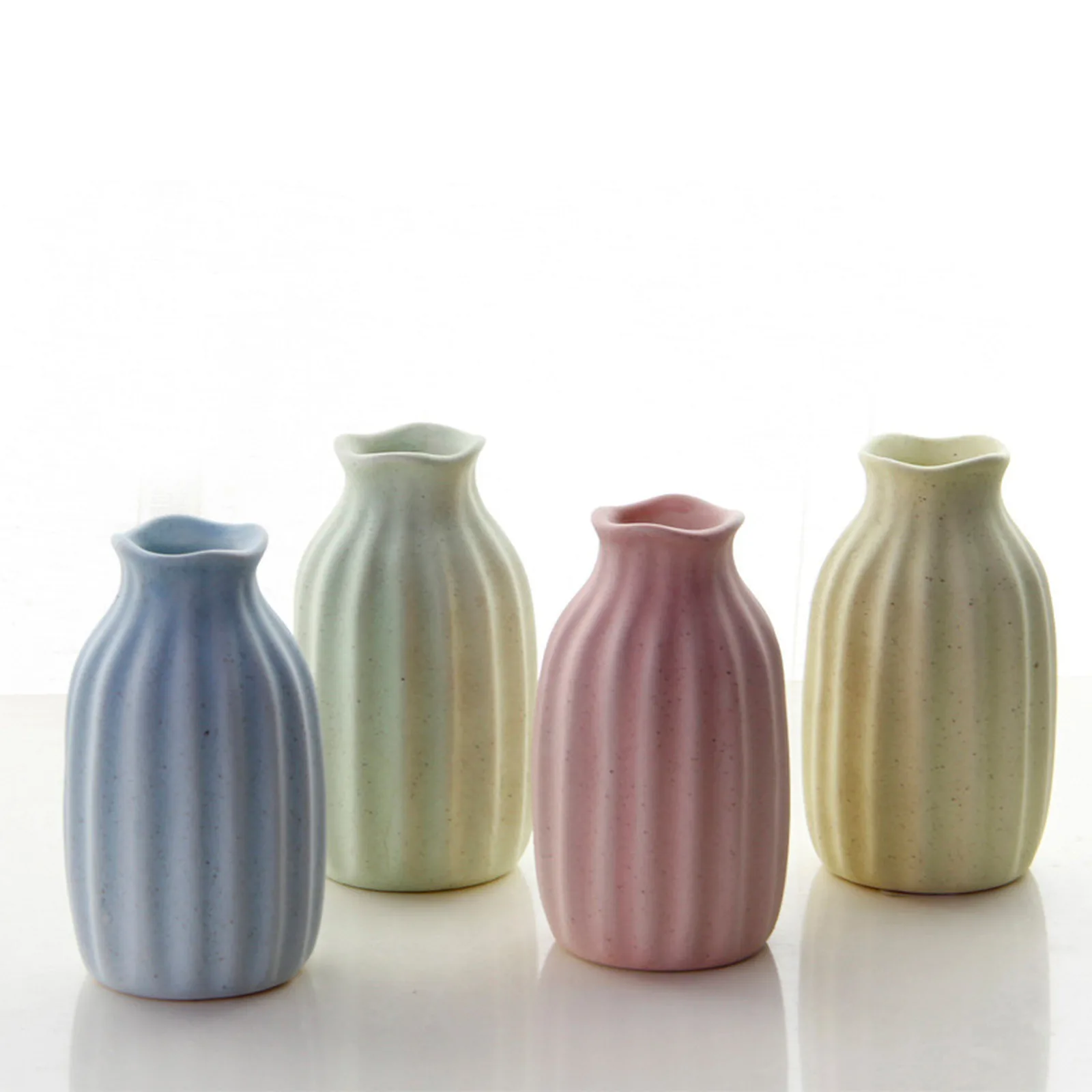 Four ribbed ceramic bud vases in blue, sage, pink and yellow