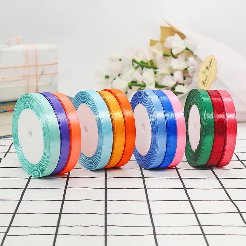 Four groups of narrow satin ribbon rolls on a grid table