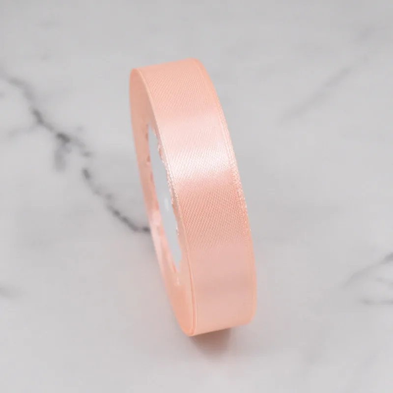 Roll of peach satin ribbon on marble