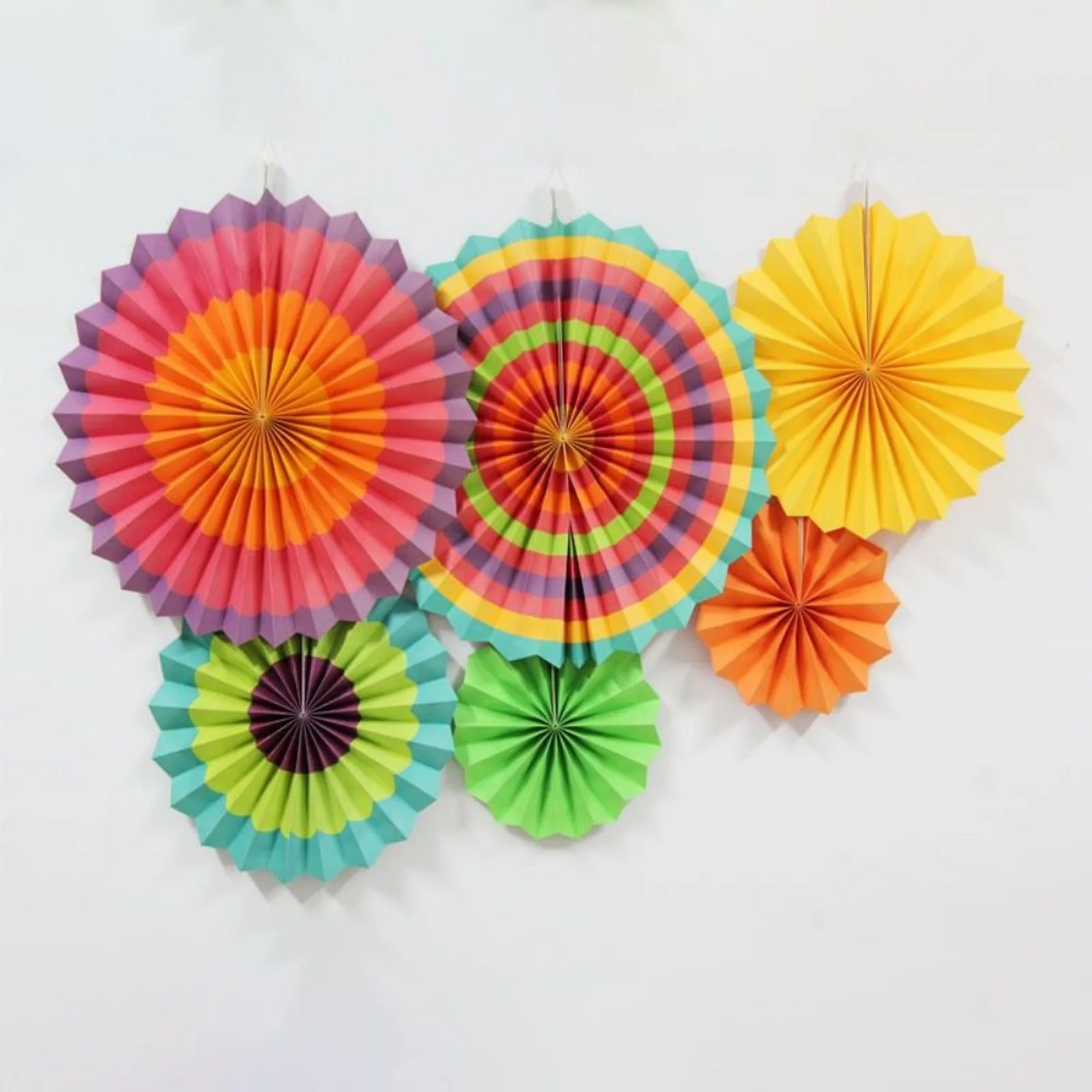 Multicolor striped paper fan set hung on a white wall